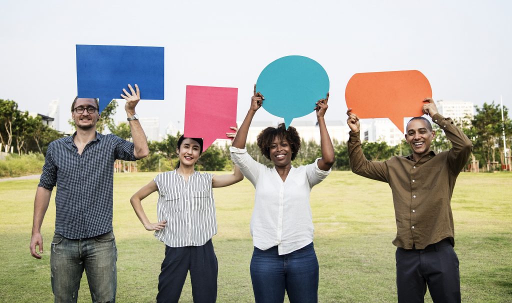 A row of four people holding blank speech bubbles above their heads