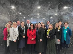 a photo of approximately 15 people in business attire standing against a marble wall