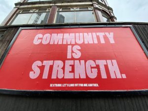 a billboard with a red background saying "community is strength"